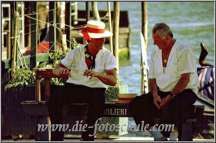 Zwei Gondolieris im Gespraech Venedig.jpg - (Tele mit 300mm, Blende offen, kurze Verschlußzeit)Zwei Gondolieris im erhitzten Gespräch, auf einer Gondel sitzend